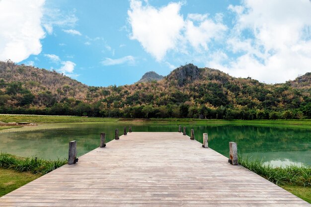 Foto puente de madera o muelle con montaña y cielo azul en el lago