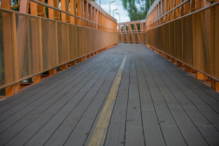 puente de madera para peatones ciclista con estructura metálica naranja señalización amarilla