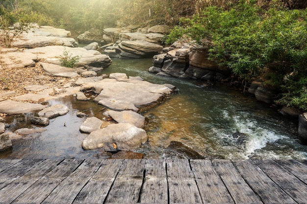 Un puente de madera sobre un río con un río al fondo.