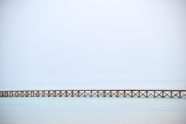 Puente de muelle horizontal largo sobre fondo de copyspace de cielo azul y agua