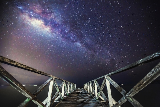 Foto puente peatonal contra la vía láctea por la noche.