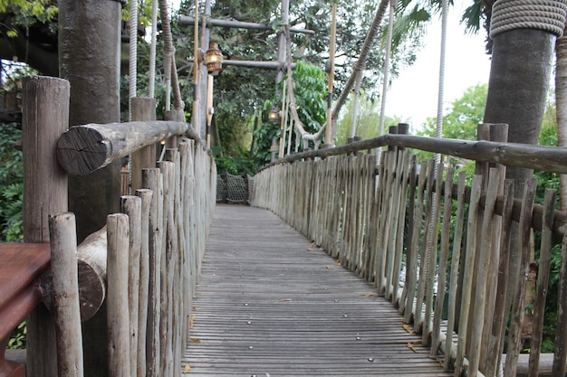 Foto puente peatonal de madera que conduce hacia los árboles