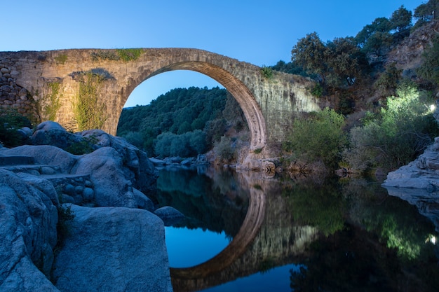 Puente de piedra sobre un río en la noche.