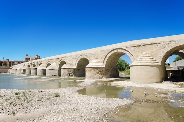 Puente romano y río Guadalquivir sobre el cielo azul brillante en Córdoba, Andalucía, España.