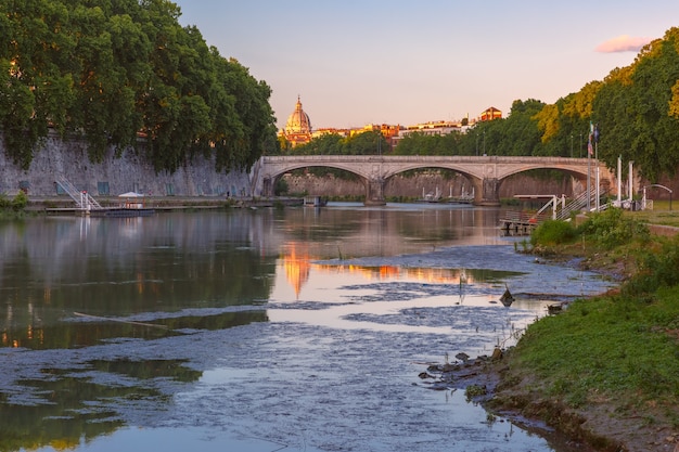 Puente de San Ángel y la Catedral de San Pedro con un reflejo de espejo en el río Tíber en la soleada mañana en Roma, Italia.