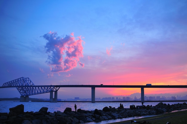 Puente de silueta sobre el río contra el cielo durante la puesta de sol