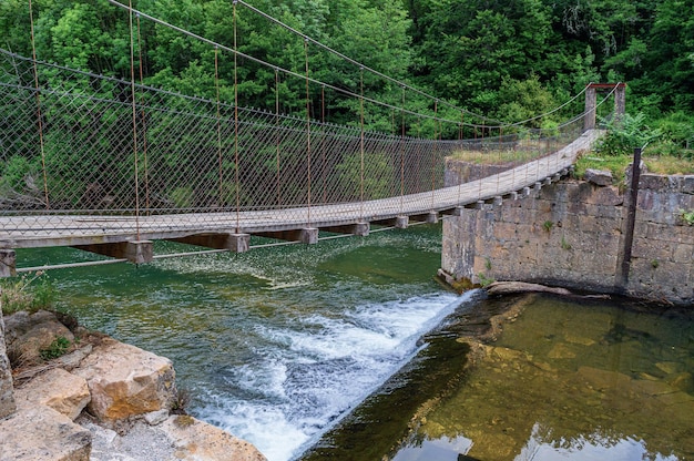 Un puente sobre un río con una cascada al fondo.