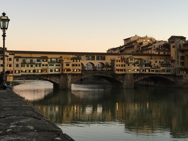 Foto puente sobre el río por los edificios contra el cielo durante la puesta de sol