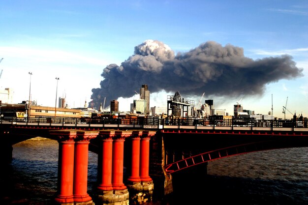 Foto puente sobre el río con humo emitiendo contra el cielo en la ciudad