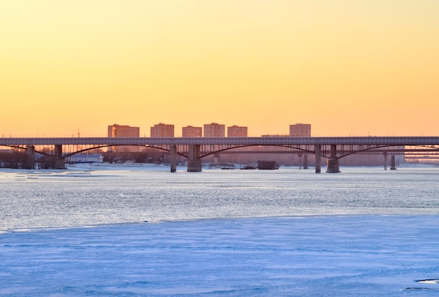 Puentes sobre un río congelado La orilla del gran río por la tarde al atardecer una nueva área urbana