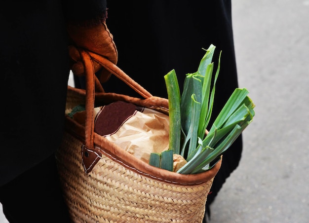 Puerro en una bolsa de paja en las manos.