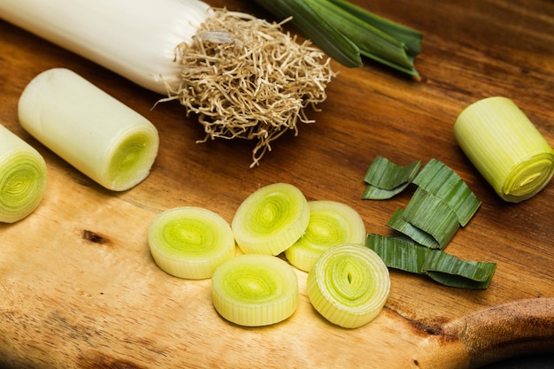 Un puerro y rodajas sobre una tabla de cocina de madera en una vista superior