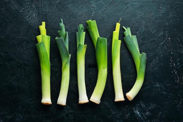 Puerro verde crudo sobre fondo negro Verduras para una alimentación saludable Vista superior Espacio de copia libre