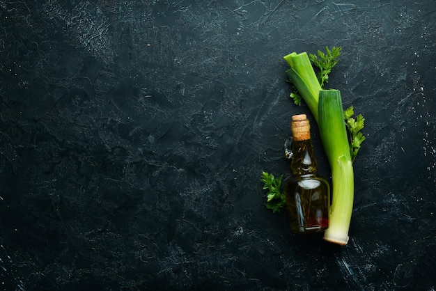 Puerros perejil y aceite sobre fondo negro Verduras para una alimentación saludable Vista superior Espacio de copia libre