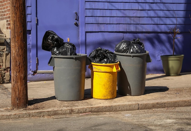 Una puerta azul está detrás de un bote de basura que dice "basura".