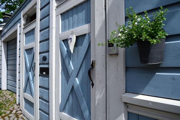 Puerta azul de madera, macetas colgantes con flores.