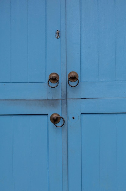 Una puerta azul tiene una manija y una perilla dorada.