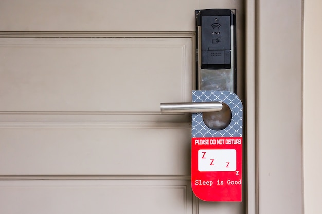 Puerta cerrada de la habitación del hotel con por favor no molestar signo colgar la perilla de la puerta