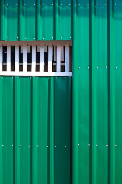 Puerta de entrada corrediza verde en pared de acero corrugado en marco vertical