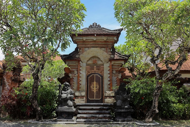 Puerta de entrada de estilo balinés rodeada por los árboles diseño exterior de fachada tradicional Bali Indones