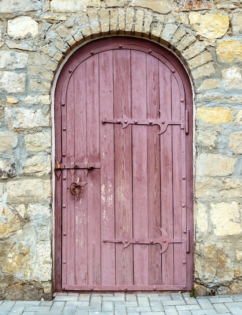 Puerta de madera antigua con cerradura en el antiguo muro de piedra