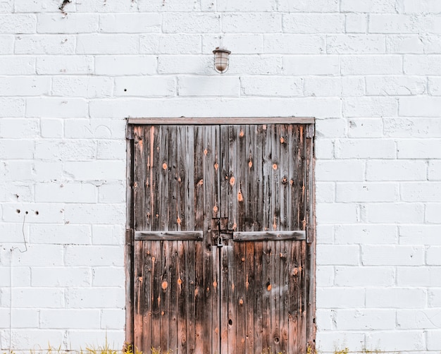 Puerta de madera antigua en una pared de ladrillo blanco.