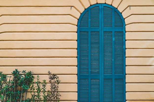 Puerta de madera arqueada azul sobre una pared amarilla