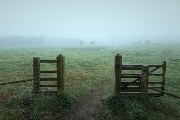 Puerta de madera en el campo y un campo cubierto de niebla Beecraigs country park Escocia