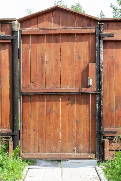 Puerta de madera cerrada alrededor del patio de la casa de campo en un día soleado.