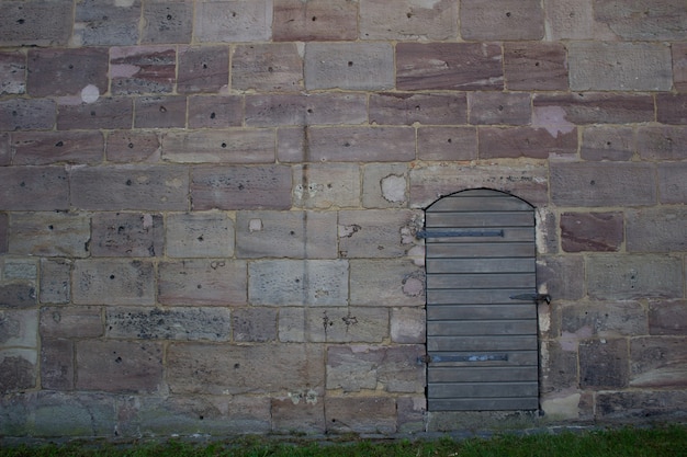 Una puerta de madera contra un muro de piedra. Camina cerca del Castillo