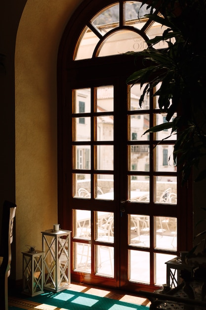 Puerta de madera marrón con vidrio que da al balcón con mesas y sillas para relajarse