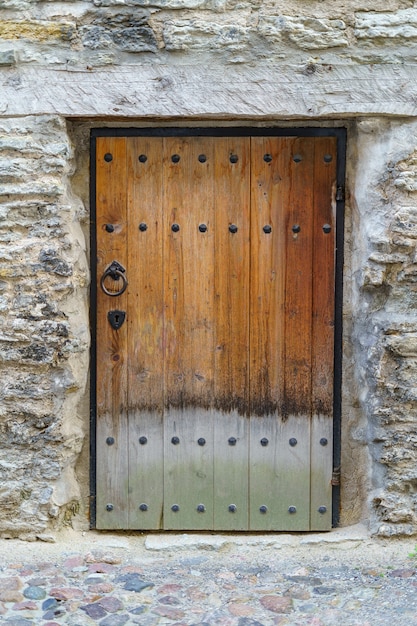 Puerta de madera muy antigua con cerradura y herrajes metálicos.