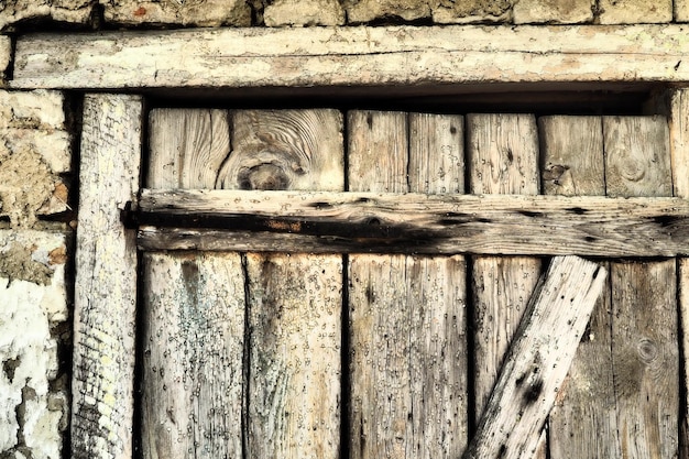 Puerta de madera vieja bloqueada de un granero rural Textura de una tabla de madera y grapas de hierro oxidadas Puerta cerrada de un edificio antiguo Edificio abandonado olvidado que se desmorona