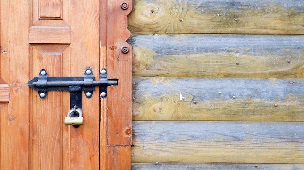 Puerta de madera vieja con un perno de metal negro. Vista de cerca de una cerradura y pestillo en una puerta de madera. Pestillo de puerta de metal de madera rústica. Esta cerradura deslizante se puede utilizar en toldos, escritorios o vallas.