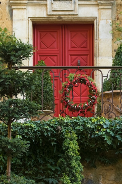 Puerta roja con Navidad con corona de conos y ramas de árboles de Navidad