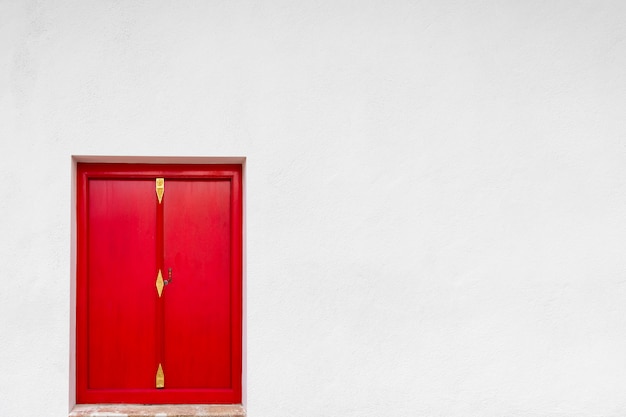 Puerta roja vieja con el fondo blanco de la pared.