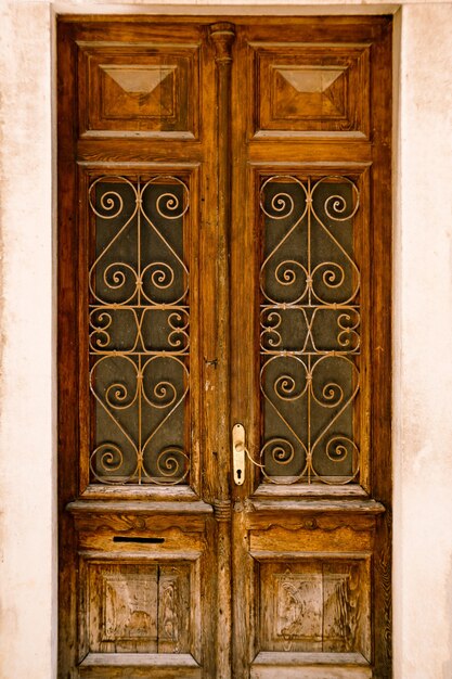 Puertas de madera con barras de vidrio de metal y patrones tallados.