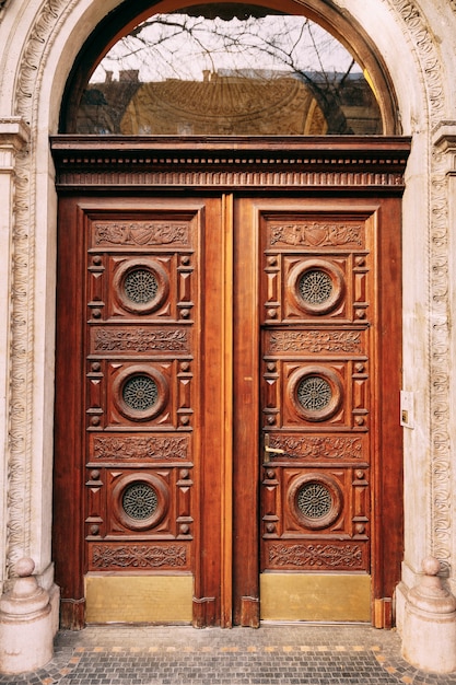 Foto puertas de madera con ventanas redondas y patrones tallados a mano.