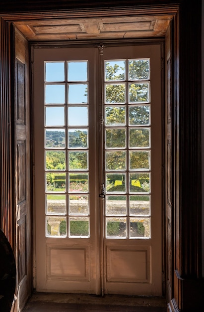 Puertas vidriadas de madera viejas que conducen al jardín adornado en la mansión vieja