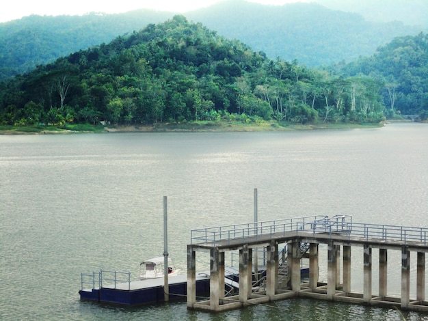 Puerto de barcos junto al lago con fondo de montañas de bosque verde brumoso