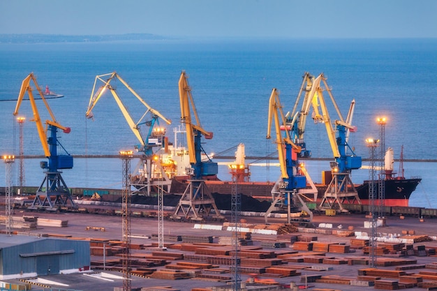Puerto comercial marítimo por la noche en Mariupol Ucrania antes de la guerra Buque de carga de carga industrial con puente de grúas en funcionamiento en el puerto marítimo al atardecer Logística del puerto de carga Industria pesada