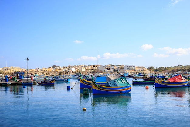 Puerto histórico de Marsaxlokk lleno de barcos de madera en Malta Cielo azul y fondo de pueblo