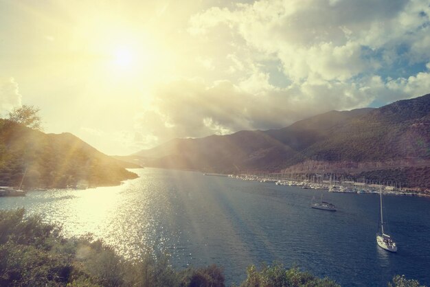 Puerto marítimo con barcos sobre un fondo de verdes montañas a la luz del sol