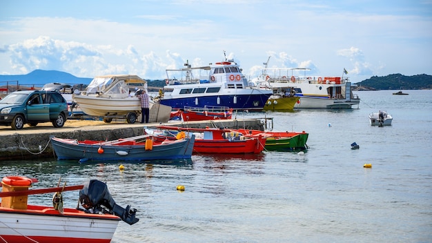 Puerto marítimo, varios barcos amarrados en el mar Egeo, un hombre enganchó un barco al coche en un muelle en Ouranoupolis, Grecia