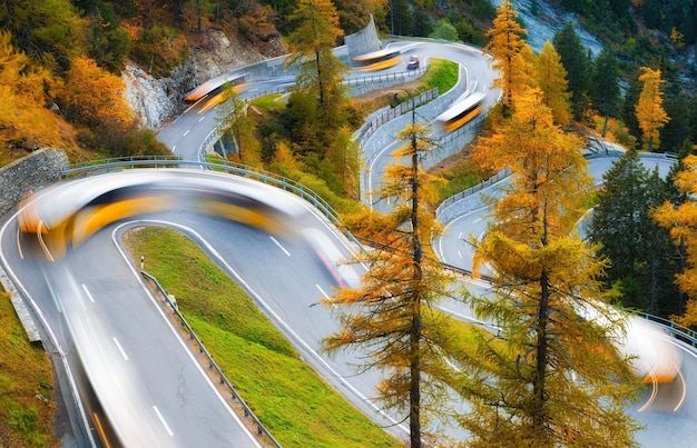 El puerto de montaña de Maloja Suiza Un camino con muchas curvas entre el bosque Luces borrosas de un autobús Paisaje en otoño Foto de gran resolución para el diseño