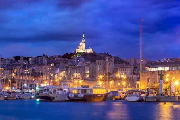 Puerto Viejo y la Basílica de Notre Dame de la Garde en el fondo de la colina por la noche, Marsella, Francia