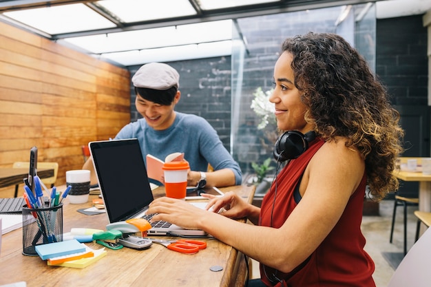 Foto puesta en marcha de dos personas multiétnicas discutiendo alegremente ideas en un espacio de coworking moderno