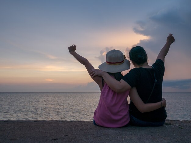 Puesta del sol alegre del fondo de la muchacha en el mar