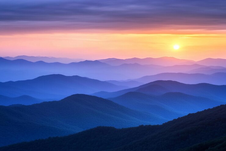 La puesta de sol arroja colores cálidos sobre las tranquilas cadenas montañosas creando impresionantes siluetas y capas