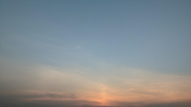 Una puesta de sol con un avión volando en el cielo.